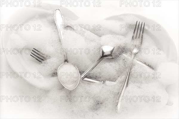 Freshly washed crockery and cutlery in soapy water