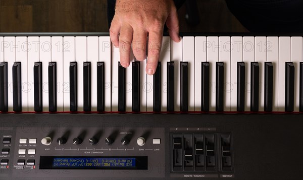 Male hands practicing on the electronic piano keyboard