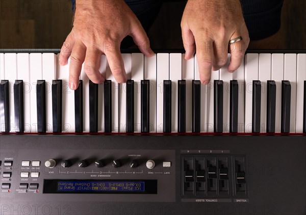Male hands practicing on the electronic piano keyboard