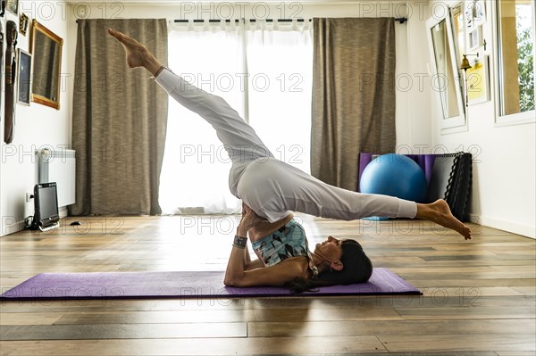 Side view of a woman practicing yoga on a mat