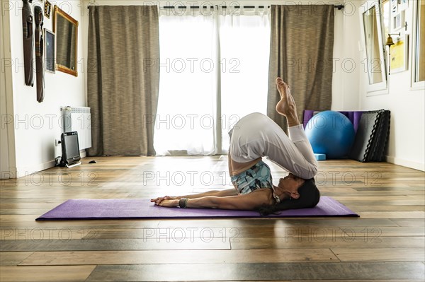 Side view of a woman practicing yoga on a mat