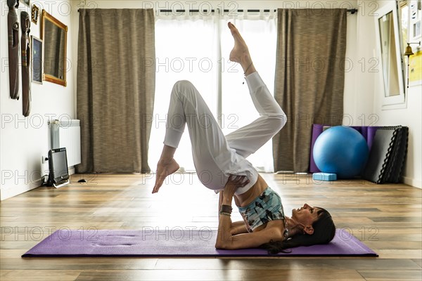 Side view of a woman practicing yoga on a mat