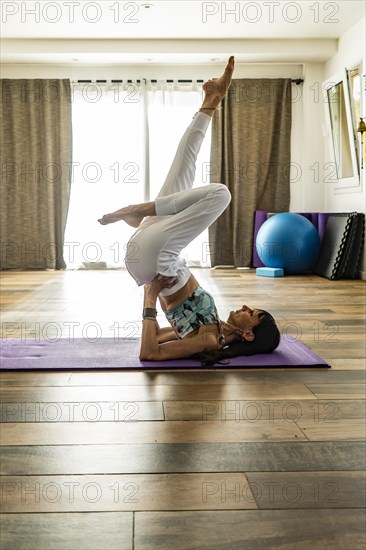 Side view of a woman practicing yoga on a mat