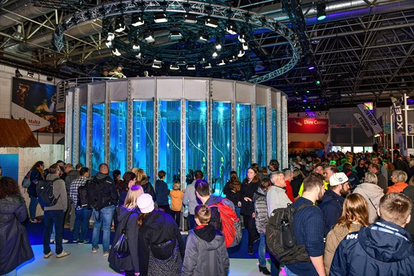 Spectators surround fair visitors looking in new diving tower in exhibition hall of water sports fair boot