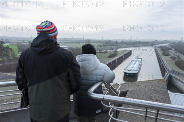 Onlookers look at a newly built tanker being manoeuvred by a push boat into Rothensee lock