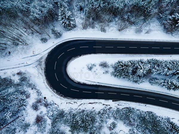 Aerial view of an S-curve in the forest with snow