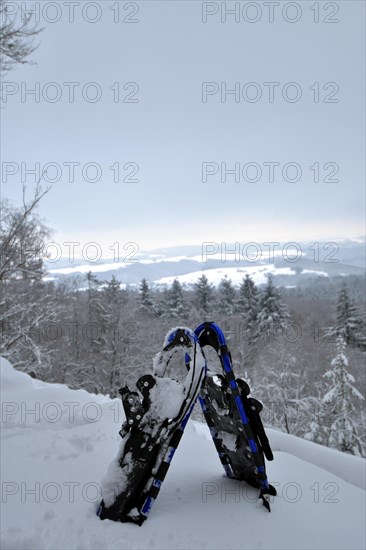 View from the mountain Moerschieder Burr in the Hunsrueck-Hochwald National Park of the snow-covered landscape with snowshoes in the foreground