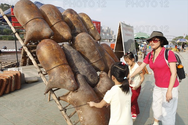 Children look at traditional inflatable boats made of goatskin on the banks of the Yellow River