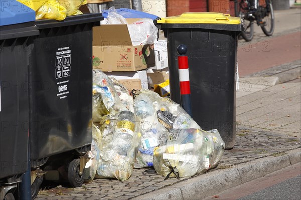 Blue bins for waste paper and yellow sacks and yellow bins for plastic waste standing on the street