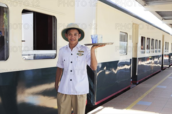 Steward in work uniform of North Borneo Railway serving drinks