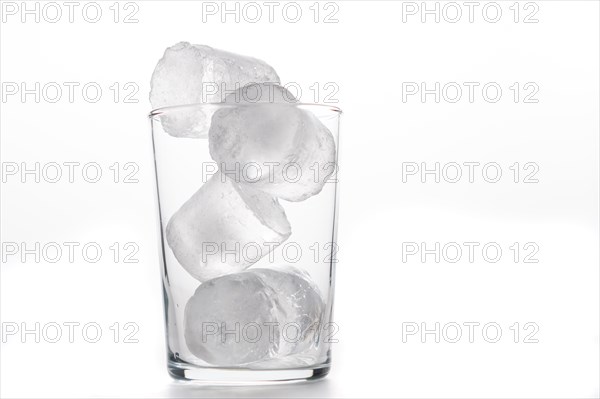 Glass tumbler with ice cubes foreground white background and copy space