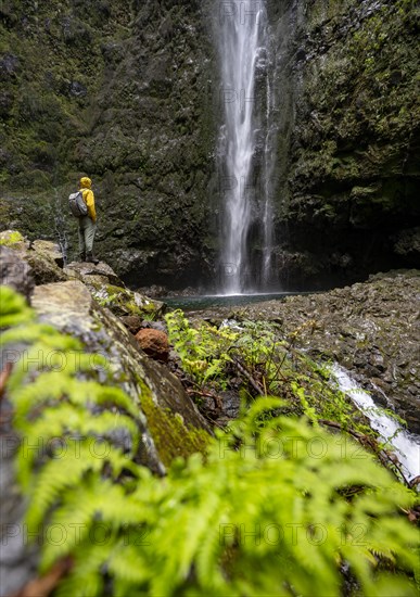 Hikers in front of a waterfall on a steep rock face