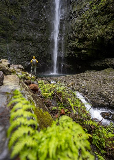 Hikers in front of a waterfall on a steep rock face