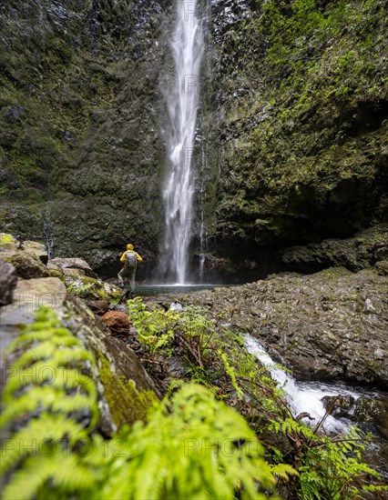 Hikers in front of a waterfall on a steep rock face