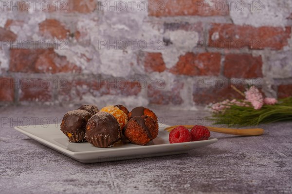 Sweet truffles of different flavors on a white ceramic plate