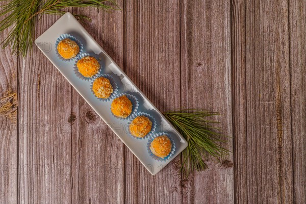 Sweet truffles in different flavors on a white ceramic tray on a wooden table