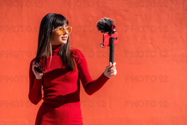 Brunette girl making the victory sign recording a video blog with the mobile