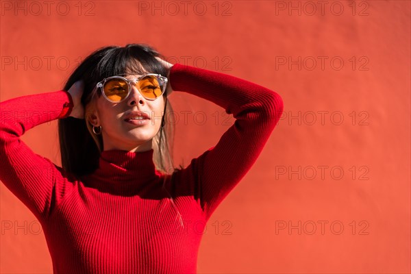 Posing brunette girl smiling in a dress and orange sunglasses in spring