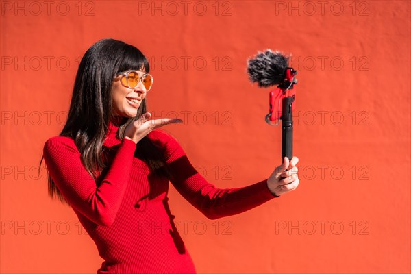 Brunette girl making the victory sign recording a video blog with the mobile