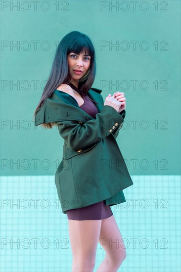 Brunette model smiling in a streetyle in a green jacket