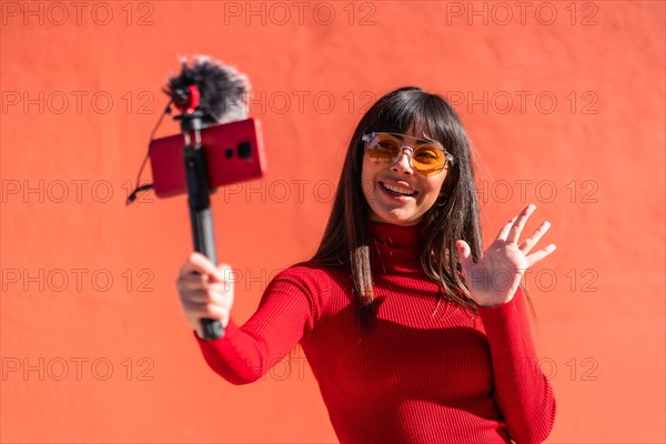 Brunette girl making the victory sign recording a video blog with the mobile