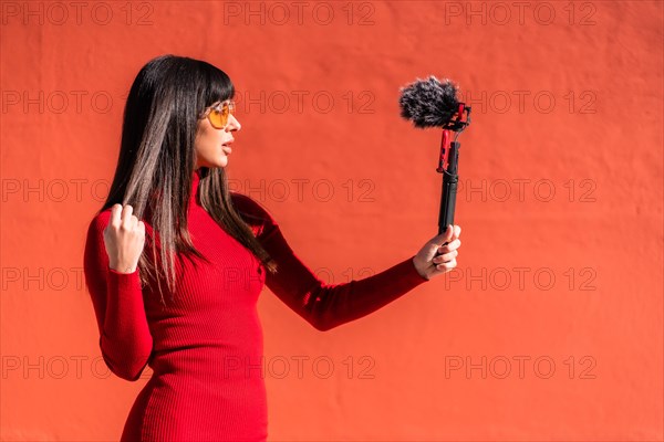 Brunette girl making the victory sign recording a video blog with the mobile