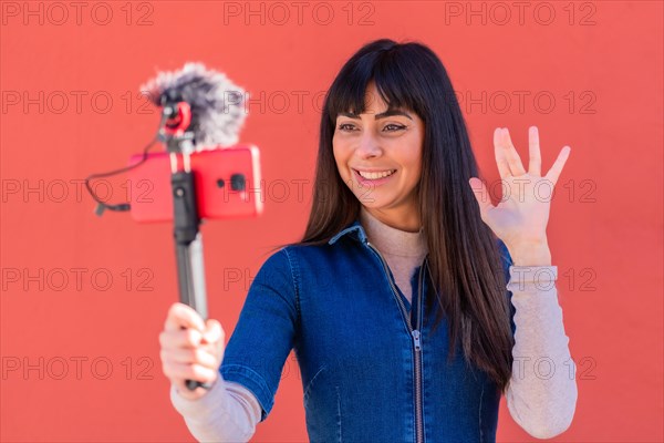 Brunette girl recording a video blog with the mobile phone in a blue denim outfit for social networks