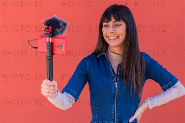 Brunette girl recording a vlog in a blue denim outfit