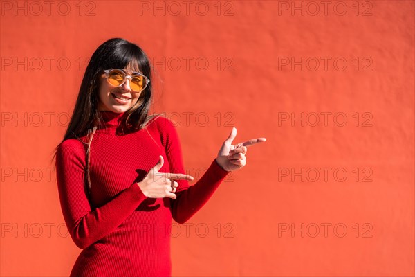 Brunette girl in an orange dress and sunglasses in spring