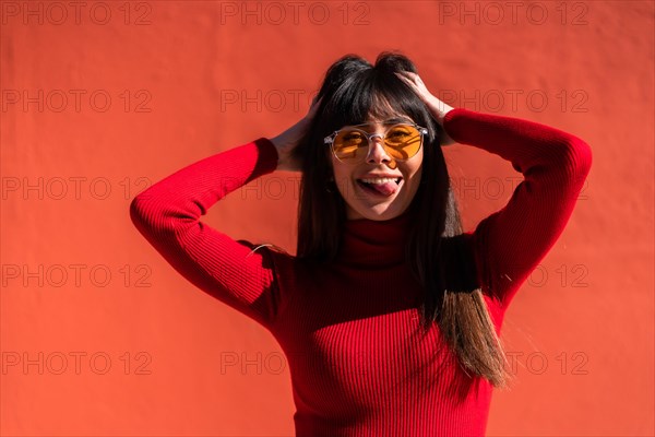 Posing brunette girl smiling in a dress and orange sunglasses in spring