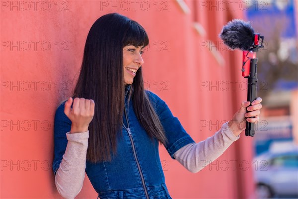 Brunette girl recording a video blog with the mobile phone and microphone