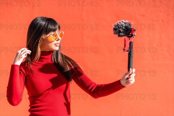 Brunette girl making the victory sign recording a video blog with the mobile