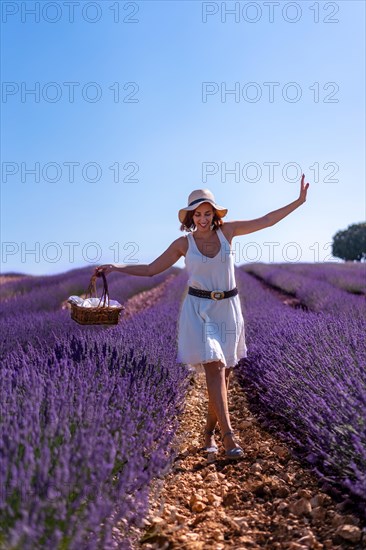 A caucasian woman in a summer lavender field with a hat picking flowers