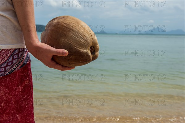 Young man holding a coconut on the beach