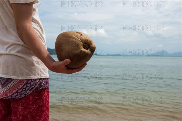 Young man holding a coconut on the beach