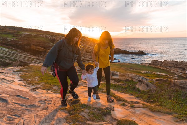 Lgbt couple of women with a child at sunset on the coast by the sea