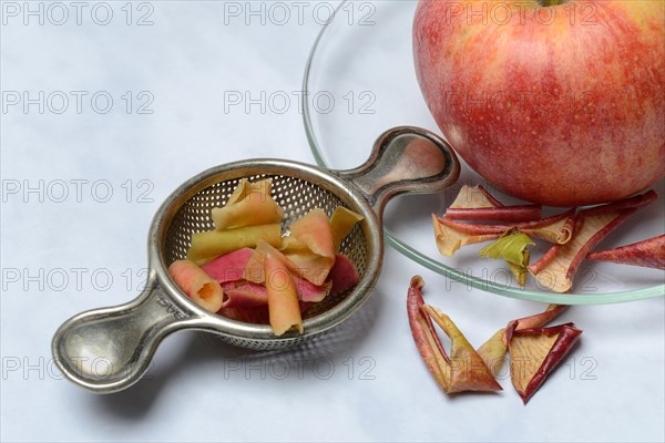 Apple peel tea in tea strainer and apple