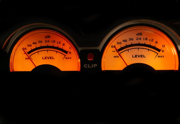 Decibel meter of a sound amplifier illuminated orange on black background