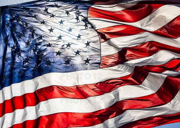 Backlit american flag waving in wind against a deep blue sky