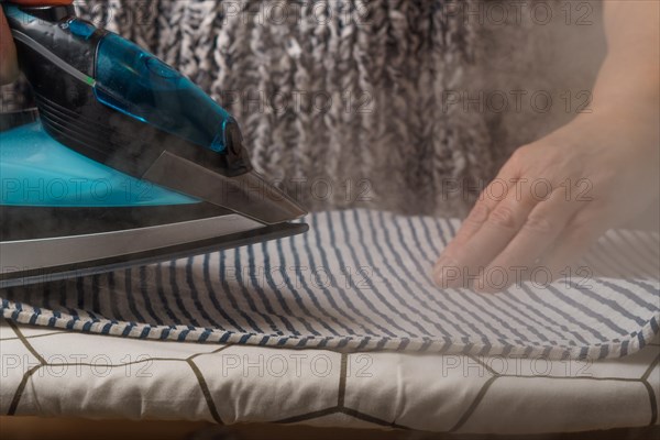 Woman ironing a striped T-shirt by steaming the iron