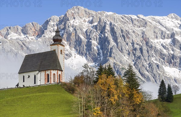 Parish church in autumnal landscape with Hochkoenig