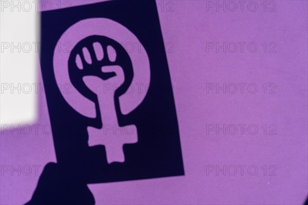 Shadow of the symbol of the fight for feminism on a purple background