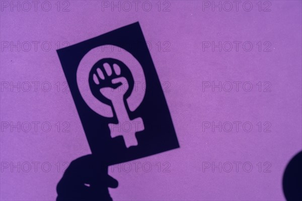 Shadow of the symbol of the fight for feminism on a purple background