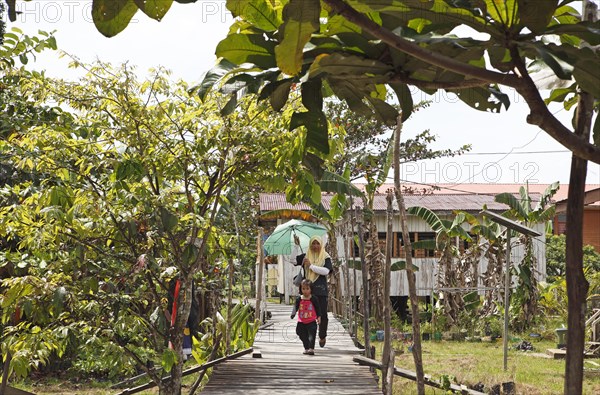 Woman with parasol on the plank path in Abai Village