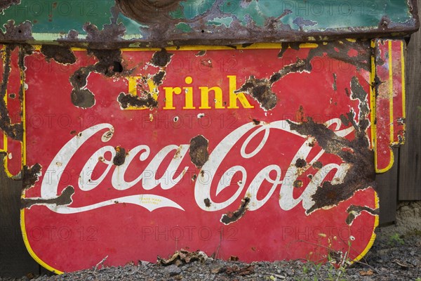 Vintage Drink Coca Cola advertising sign in front of wood plank storage shed