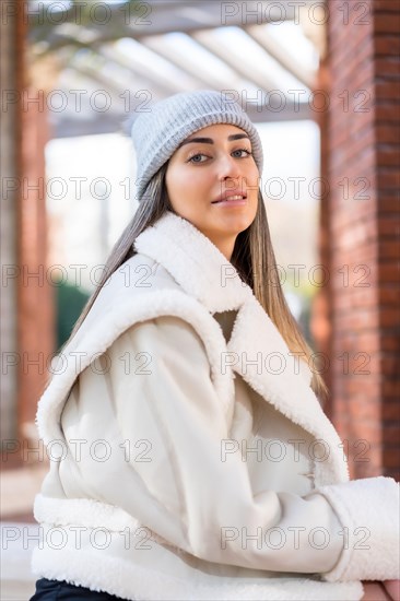 Pretty caucasian woman in a wool hat sitting in a city park