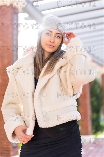 Pretty caucasian woman with wool cap in a city park at sunset
