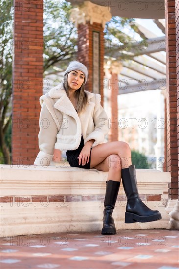 Caucasian woman in a wool hat sitting in a city park looking at camera