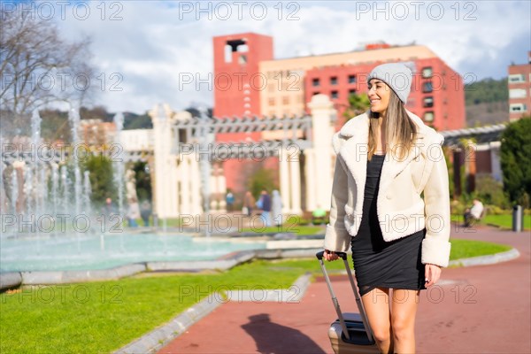 Caucasian woman in a wool hat in a city park next to a water fountain