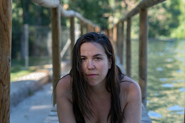 Attractive young long-haired brunette girl in a black swimsuit looking at the camera in a pontoon